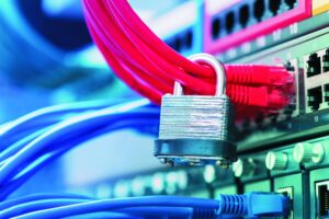 Das Bild zeigt mehrere Netzwerkkabel, die in einen Server oder Switch eingesteckt sind. Ein silbernes Vorhängeschloss sichert die roten Kabel und symbolisiert den Schutz digitaler Infrastruktur. Die Aufnahme steht sinnbildlich für IT-Sicherheit, Datenschutz und den Schutz vor unbefugtem Zugriff.